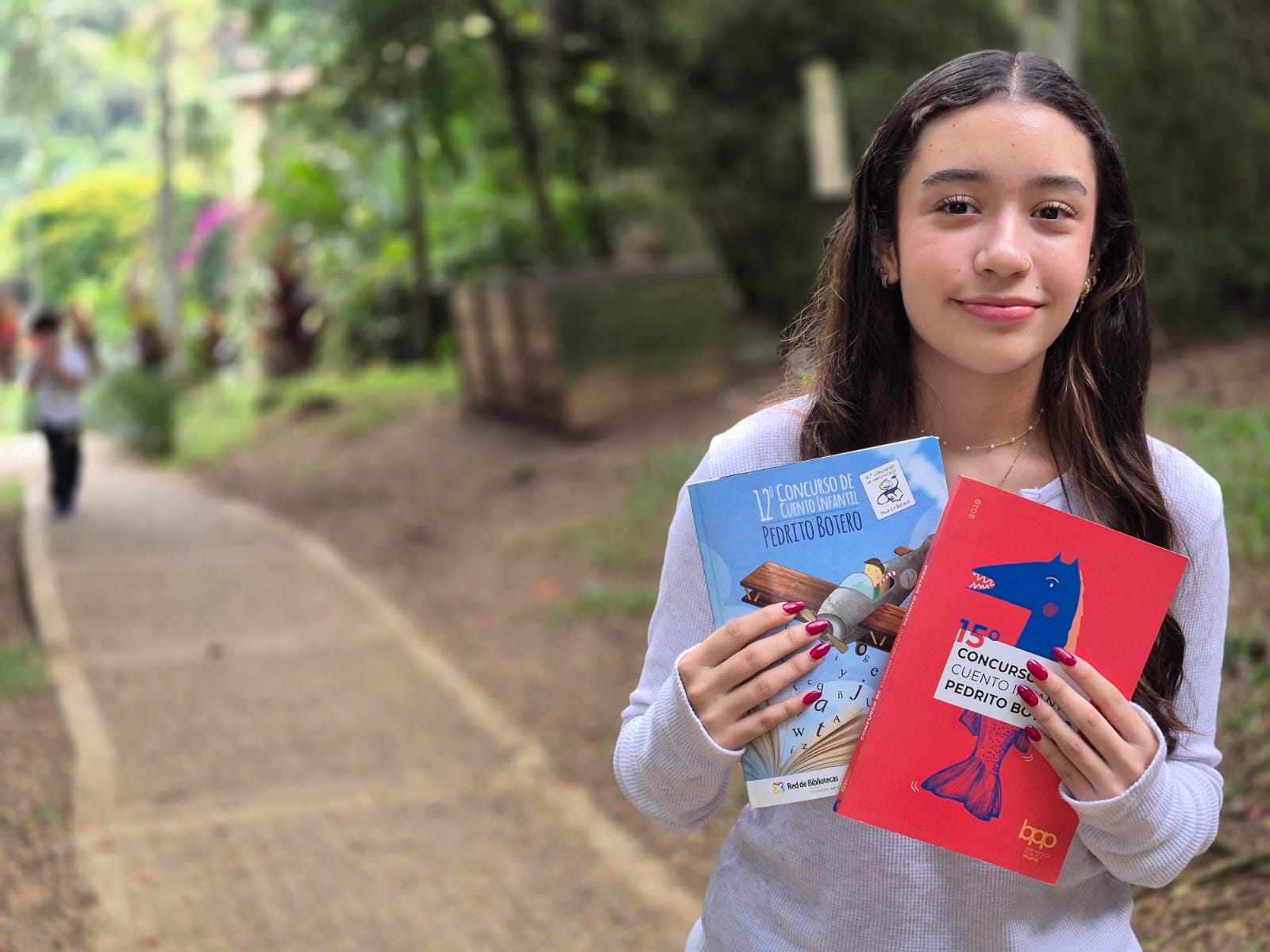 Luciana con los libros de los cuentos ganadores y finalistas del concurso en 2016 y 2019, años en los que ella ganó.