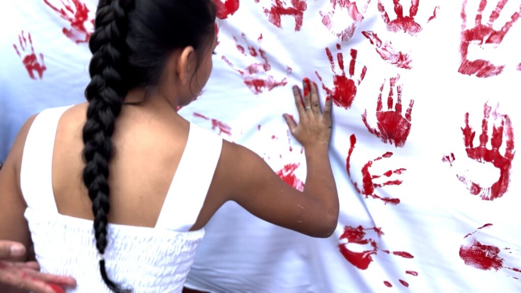 Niños plasmando manos rojas en mural