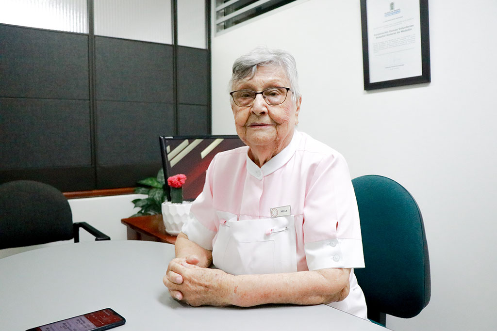 Imagen de Nelly de Arango Dama Voluntaria en su escritorio sonrriente
