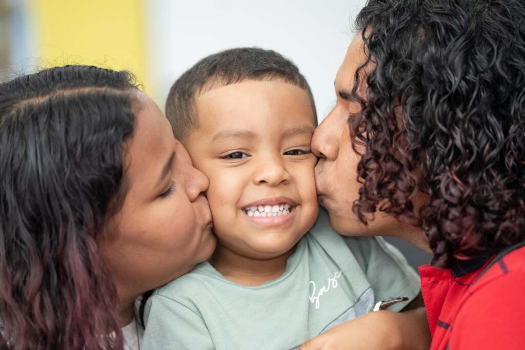 Imagen de papá y mamá besando a su hijo en el medio en taller Escuela para la familia