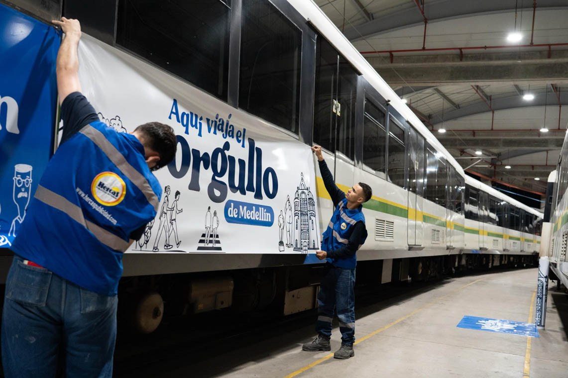 Imagen de funcionarios del Metro de Medellín instalando publicidad de la campaña ¡Qué orgullo Medellín!