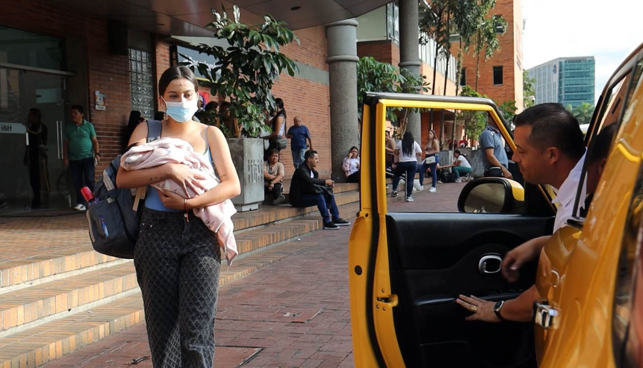 Imagen de madre gestante con su bebé tomando un taxi