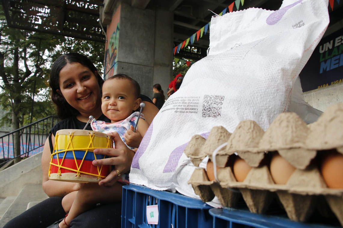 Imagen de ciudadana beneficiaria con mercado y kit pedagógico