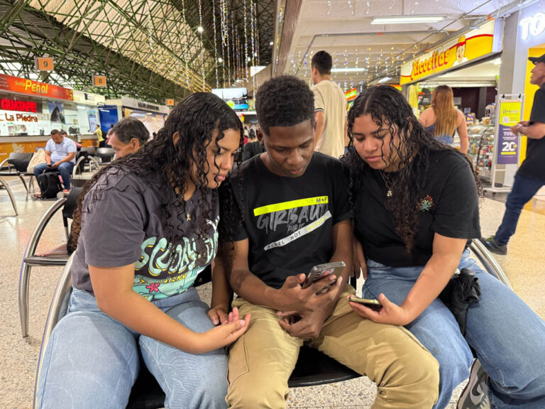 Imagen de tres ciudadanos revisando un celular