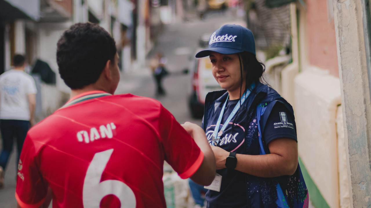 Imagen de funcionaria del Programa Parceros hablando con un joven