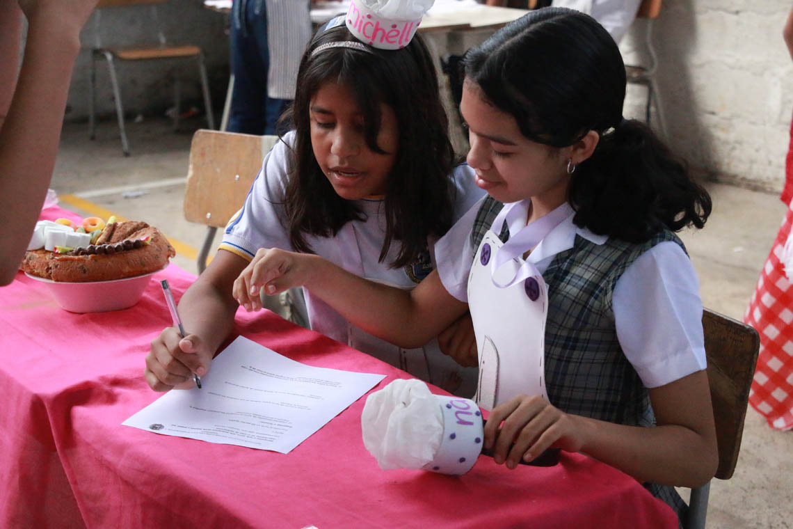 Imagen de pareja de niñas resolviendo puebas en concurso Con una pizca de matemática