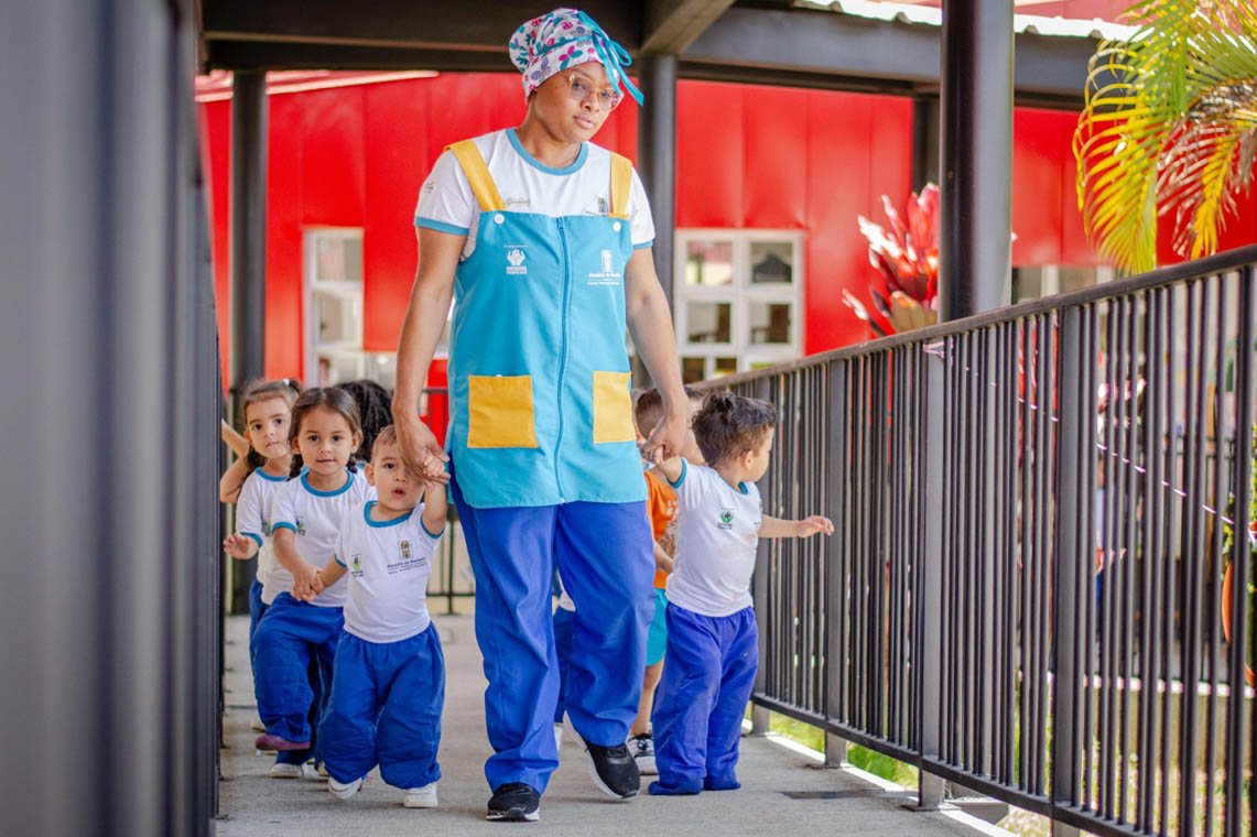 Imagen de docente con niños de Buen Comienzo tomados de la mano