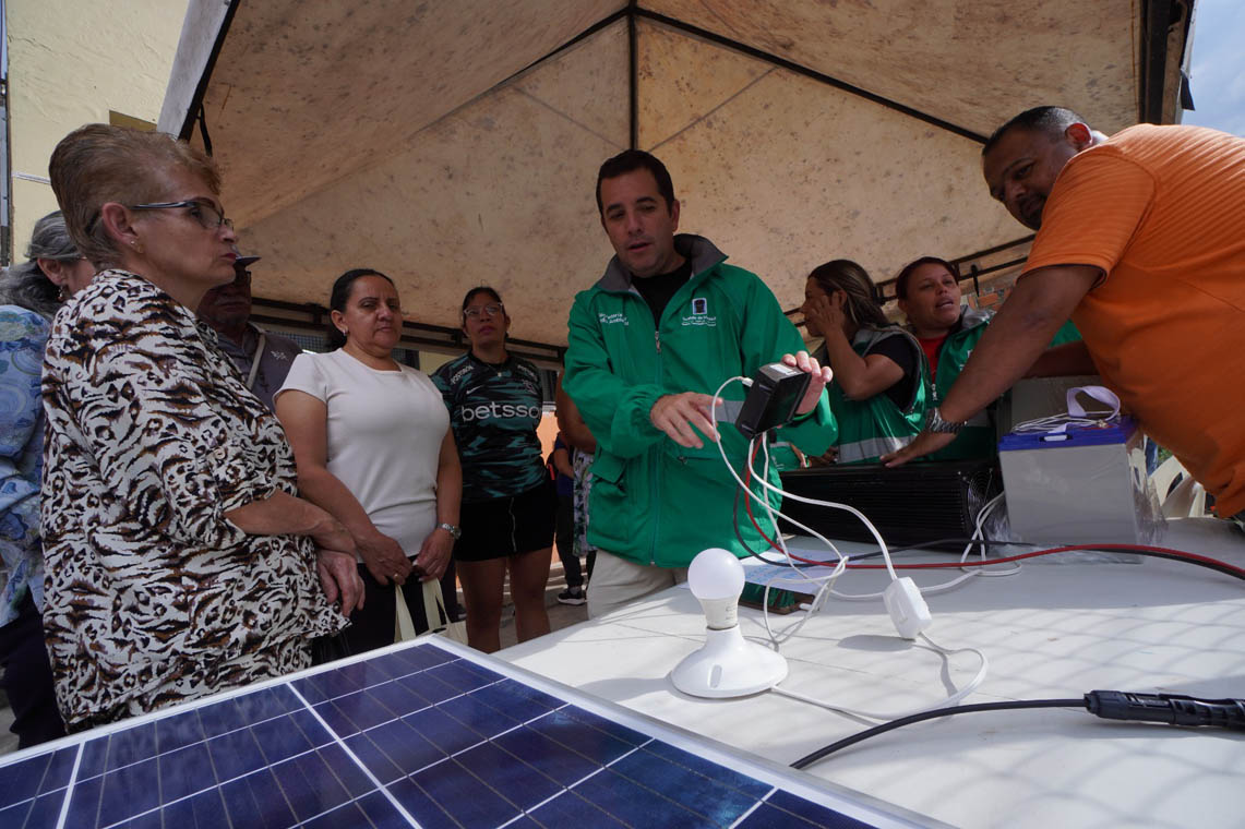 Imagen de funcionario reunido con la comunidad explicando el uso de un panel solar