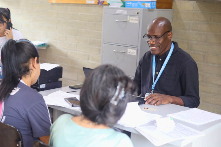 Imagen de funcionario sonriente atendiendo a ciudadanas