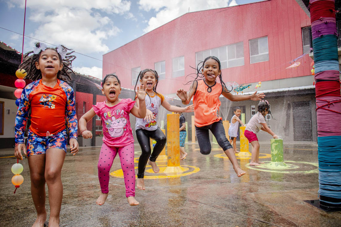 Imagen de grupo de niños sonrientes jugando en chorritos de agua