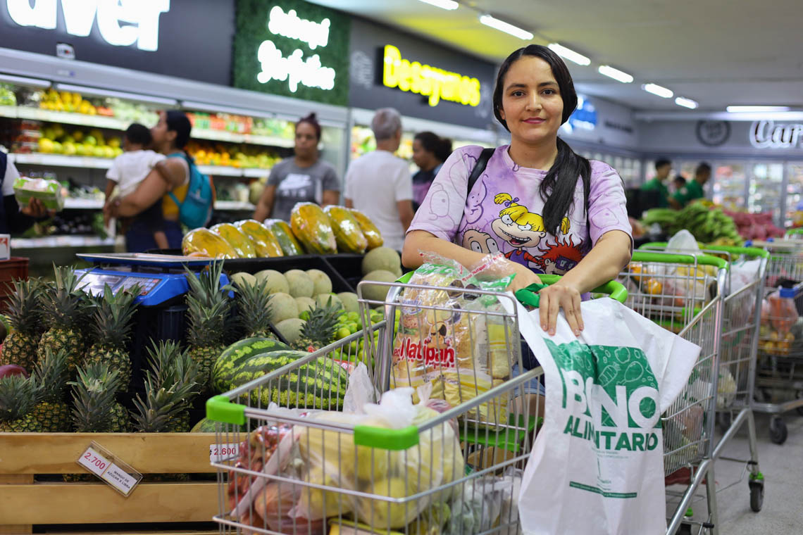 Imagen de beneficiaria de bono alimentario con carrito de productos