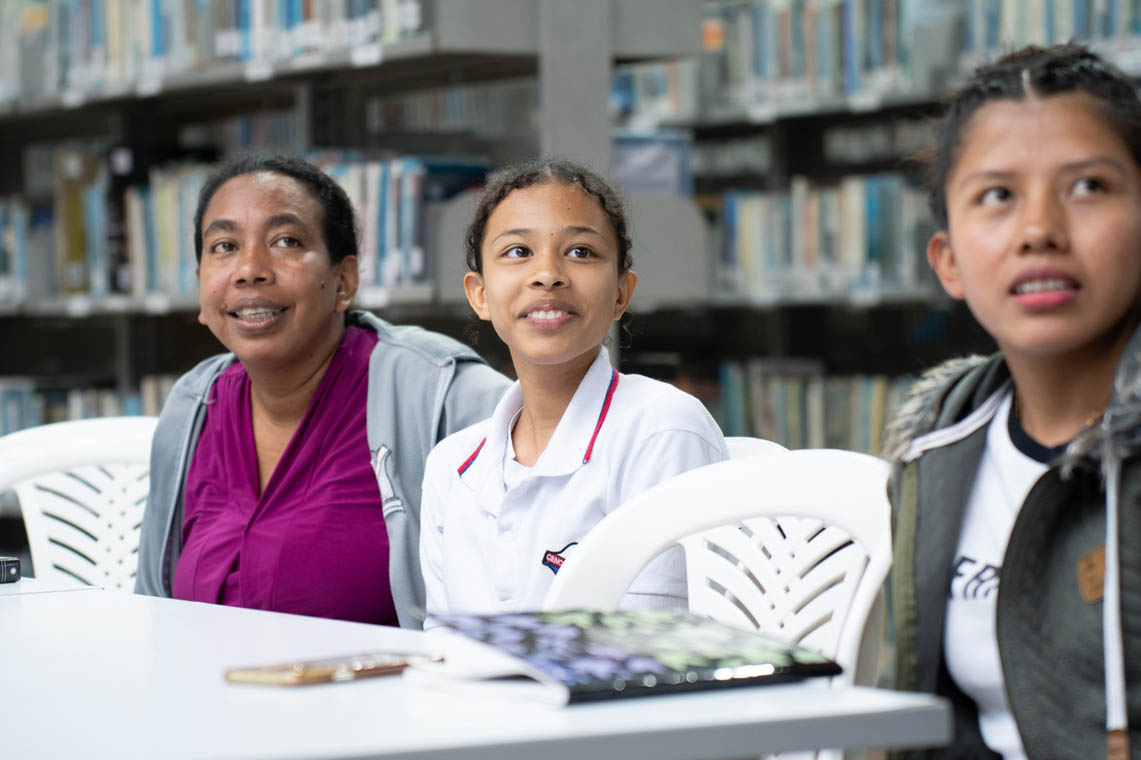 Imagen de tres jóvenes en una biblioteca