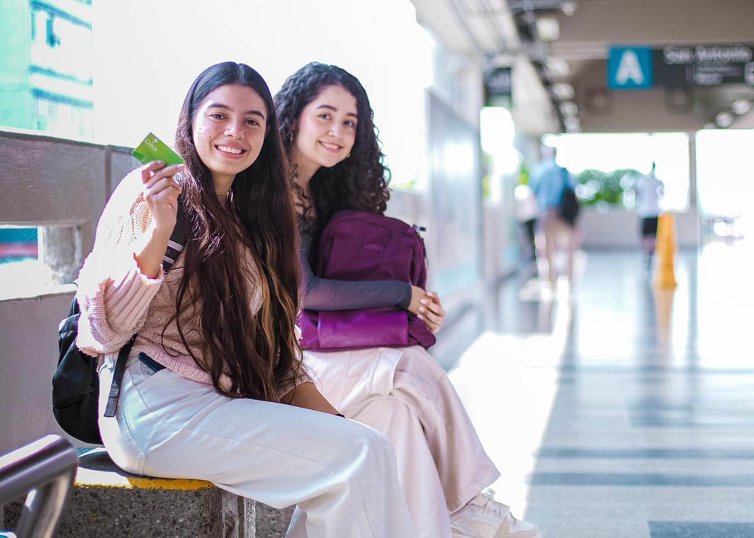 Imagen de dos jovencitas enseñando la tarjeta Cívica en plataforma del metro