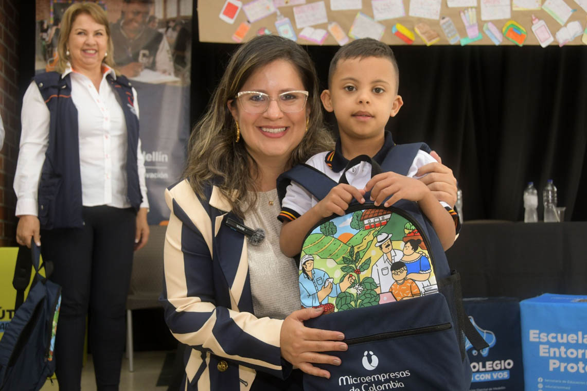 Imagen de funcionaria entregando una maleta con útiles a un niño de colegio
