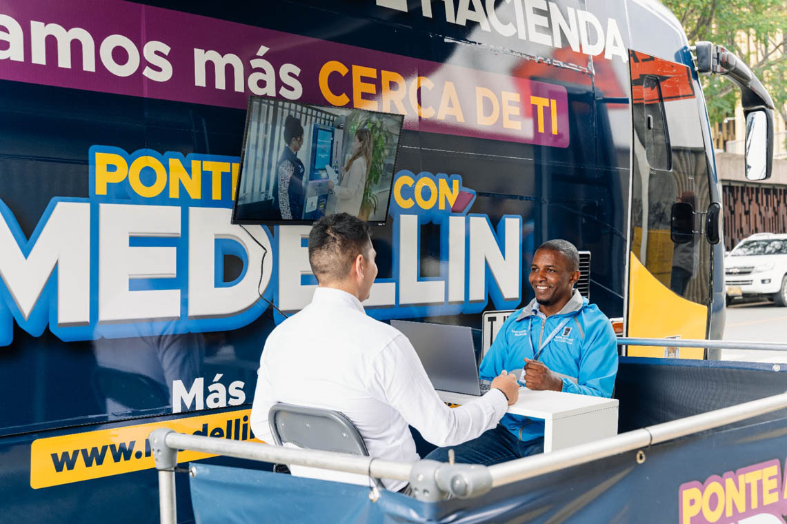 Imagen de funcionario atendiendo a ciudadano en oficina móvil de trámites tributarios