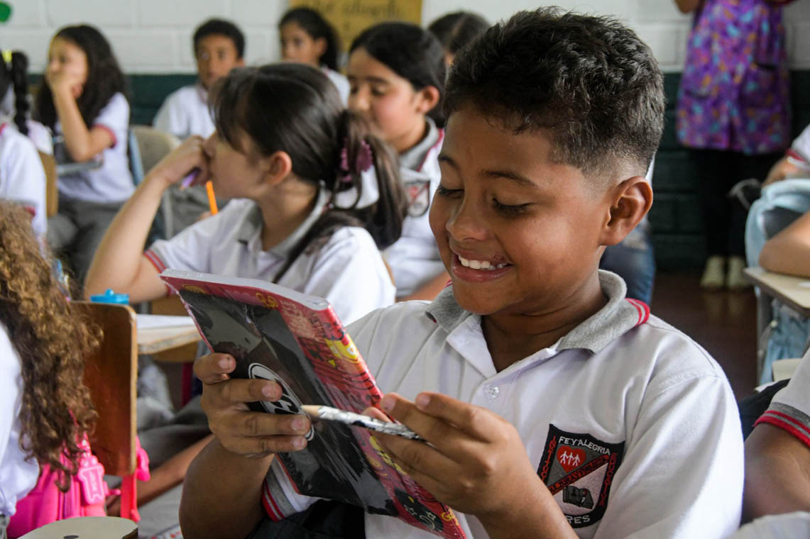 Imagen de niño sonriendo con un cuaderno nuevo