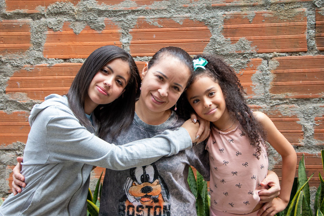 Imagen de una mujer con dos niñas abrazadas
