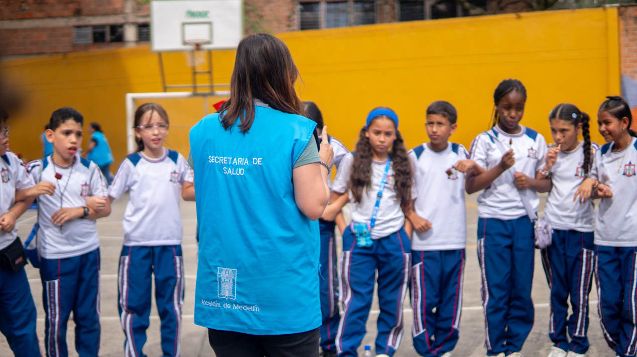 Imagen de funcionaria con estudiantes de colegio