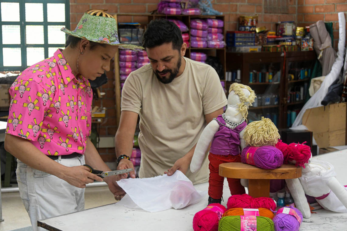 Imagen de joven y docente haciendo un corte en tela