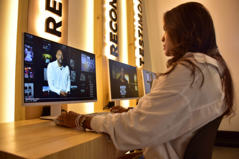 Imagen de una joven sentada en un computador viendo un video