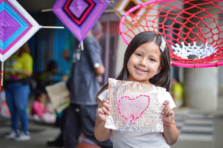 Imagen de una niña mostrando un tejido con forma de corazón