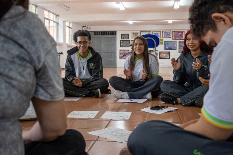 Imagen de estudiantes de colegio haciendo una actividad sentados en el suelo