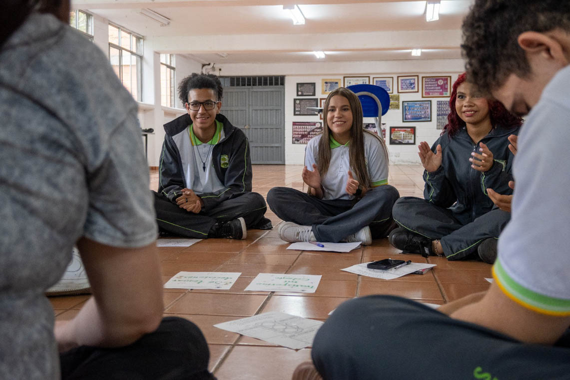 Imagen de estudiantes de colegio haciendo una actividad sentados en el suelo