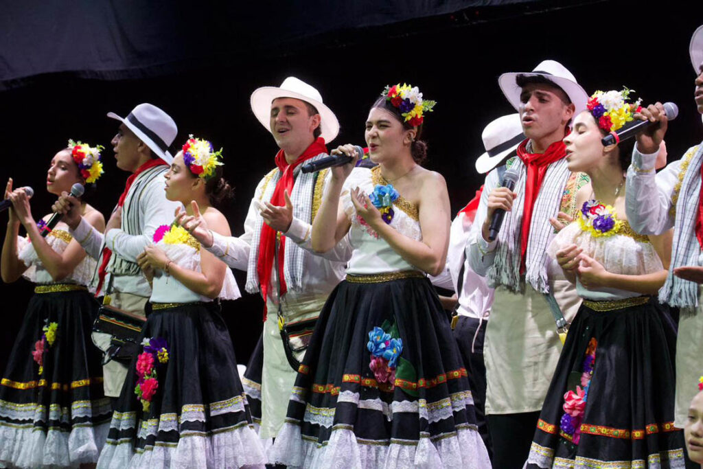 Imagen de grupo de personas cantando con trajes autóctonos