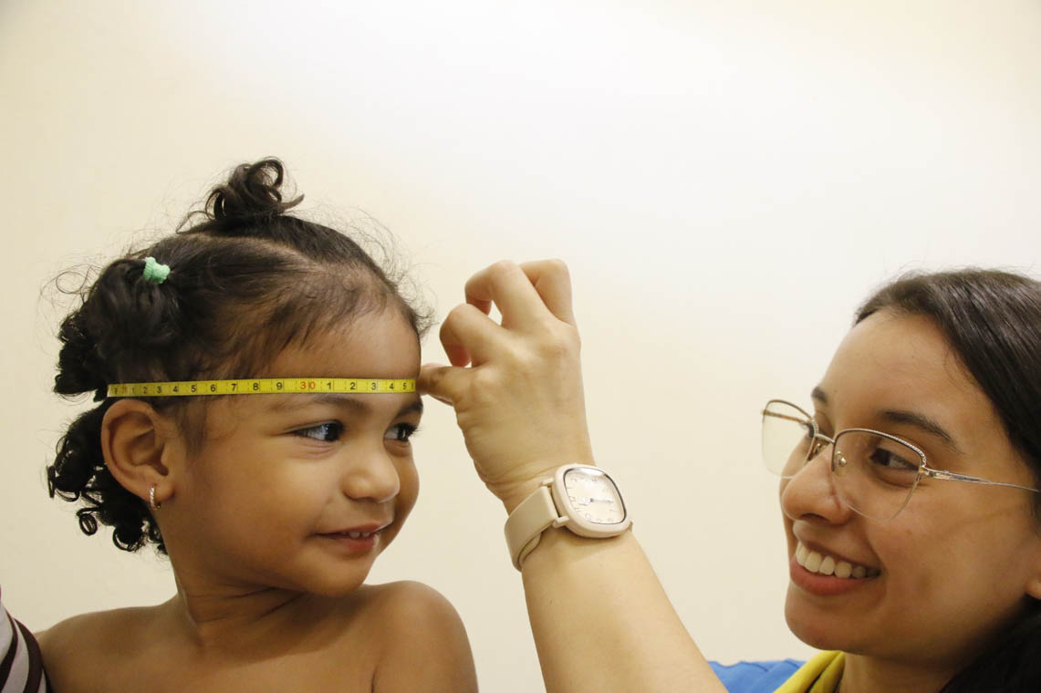 Imagen de una funcionaria de Buen Comienzo tomándole medidas de crecimiento a una niña
