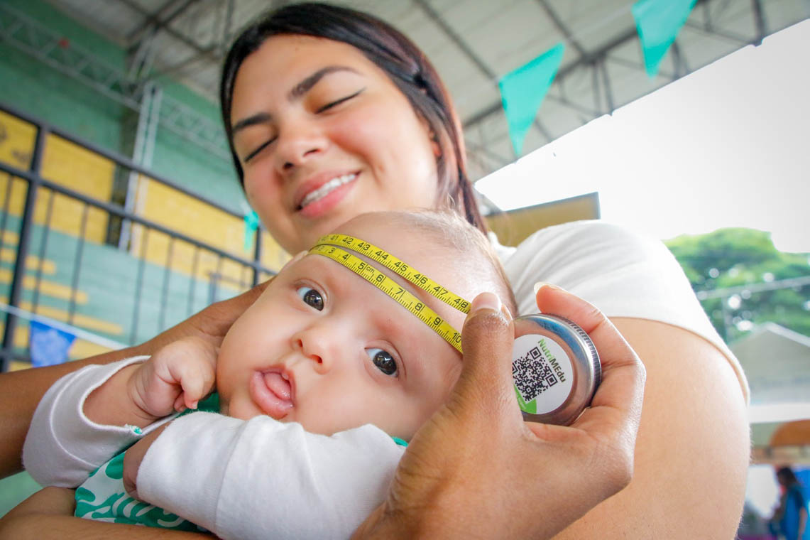 Imagen de una madre con un bebé al que le toman medidas de crecimiento